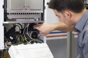 Technician inspecting and repairing the interior components of a furnace, highlighting maintenance and troubleshooting for HVAC systems.